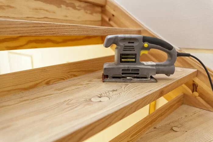 closeup of a sheet sander sitting idle on a wooden staircase