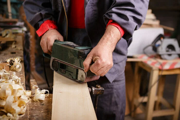 belt sander being used in a workshop to sand wood